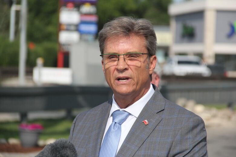 A man in a suit and tie speaks into a microphone.