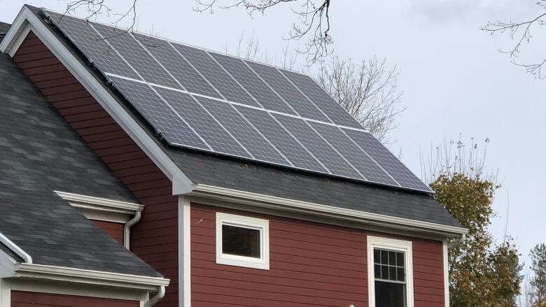 A stack of solar panels placed on a red house in Nova Scotia. 