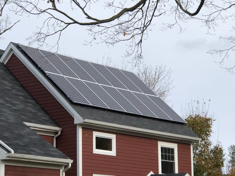 A stack of solar panels placed on a red house in Nova Scotia. 