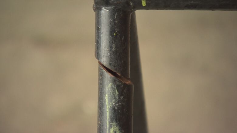 A close up shows a cut through a metal poll of a bike rack. 