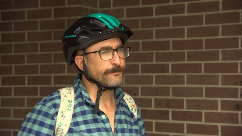 A man wearing a bike helmet speaks to a reporter off-camera. 