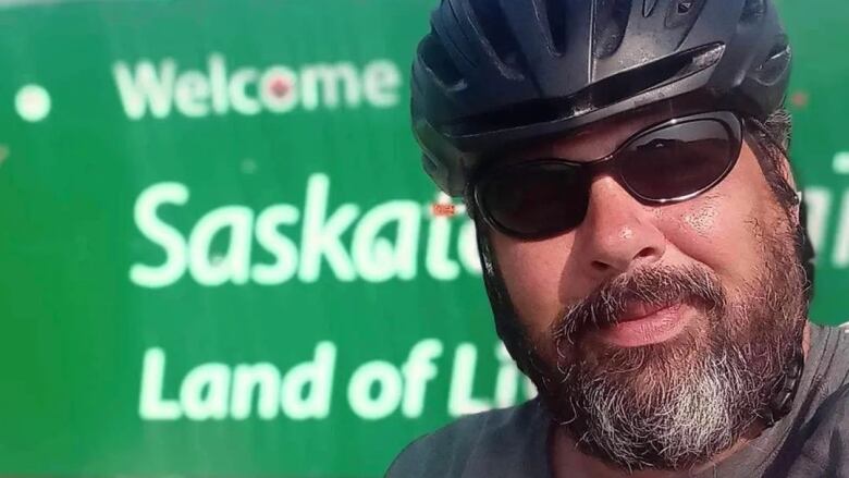 A close-up of a man wearing dark glasses and a helmet.