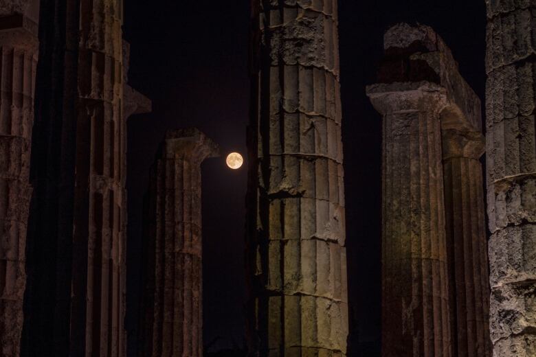 Full moon peeking between columns of an ancient temple near Athens.