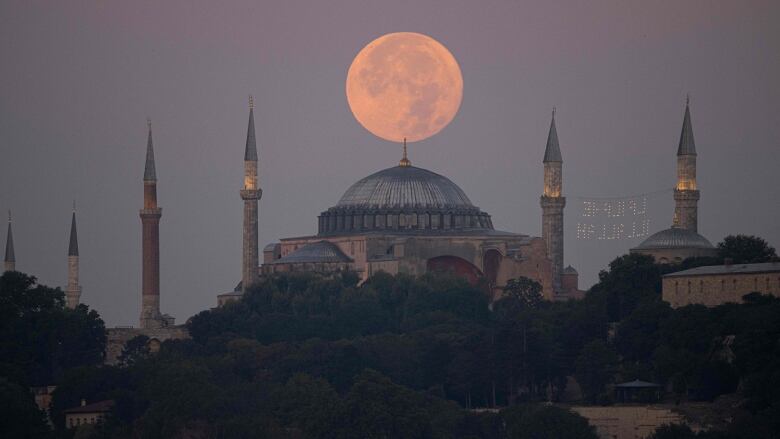 Full moon rising over a mosque.