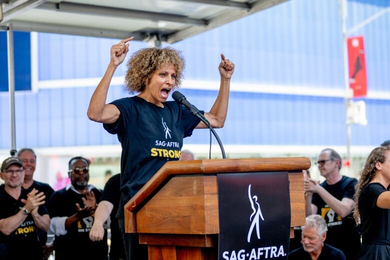 At a podium, actor Michelle Hurd speaks to a crowd during a rally in Times Square in New York.