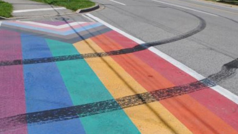 A pride crosswalk with dark black skid marks through it