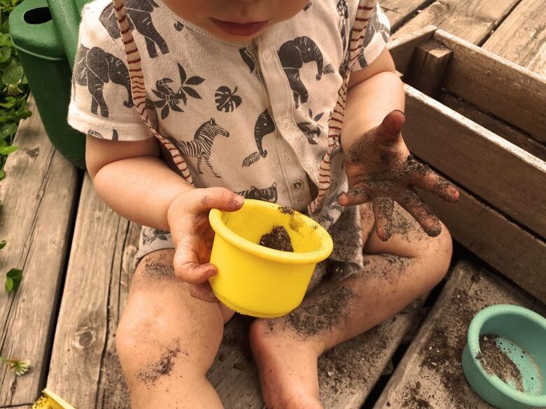 A toddler plays in a garden.