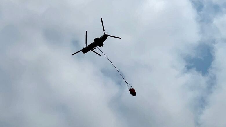 A helicopter flying with a bucket of water