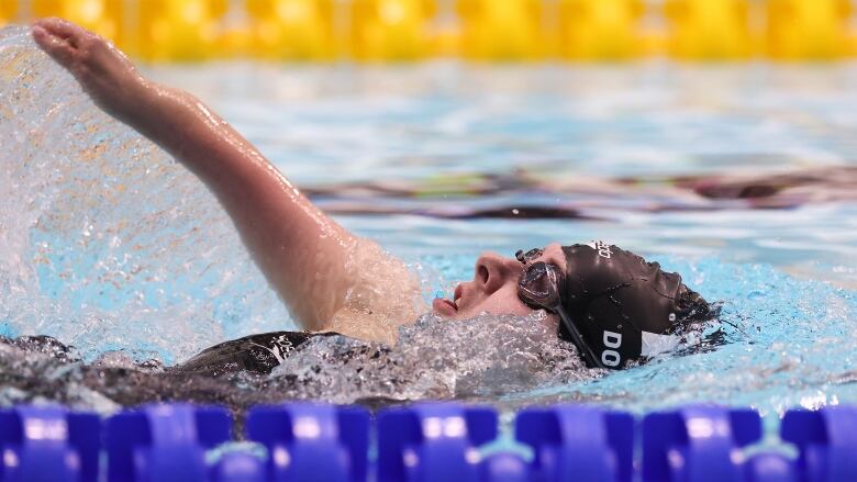 A swimmer does backstroke in the pool.