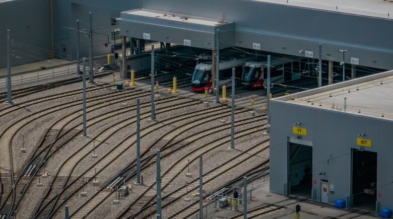 White-and-red light-rail vehicles sit inside a maintenance garage. Lots of criss-crossing tracks are visible.