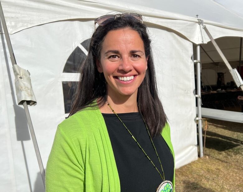 A smiling woman stands outside a big event tent.