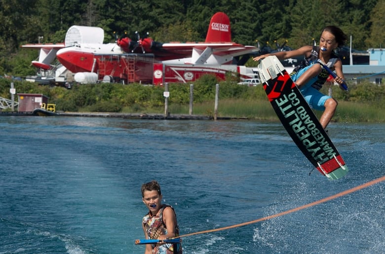 A boy on a wakeboard flies over his brother as a Martin Mars Coulson Flying Water Tanker is pictured in the background