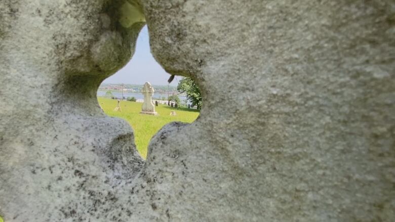 A tombstone is seen through a carved space in another tombstone.