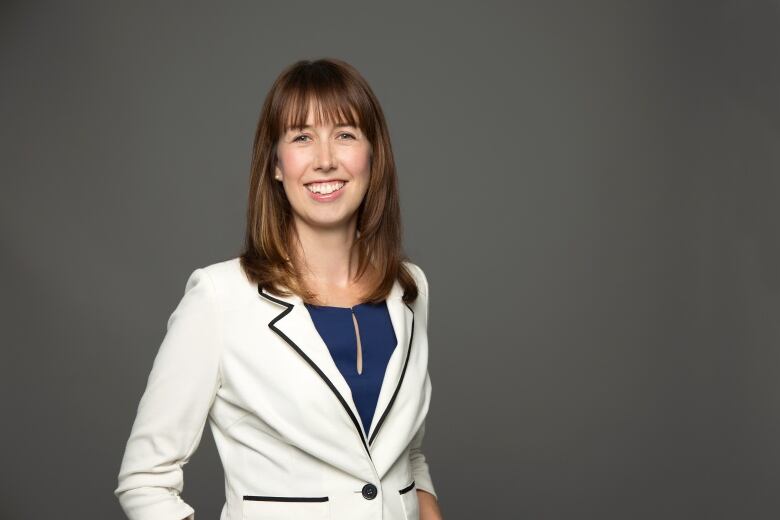 Photo of a woman in a blazer in front of a grey backdrop