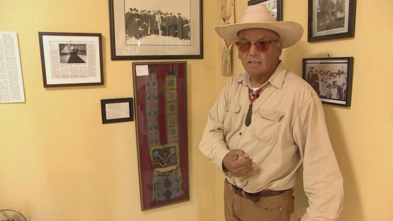 A Bandolier bag can be seen with a man in front of it, showcasing different artifacts. 