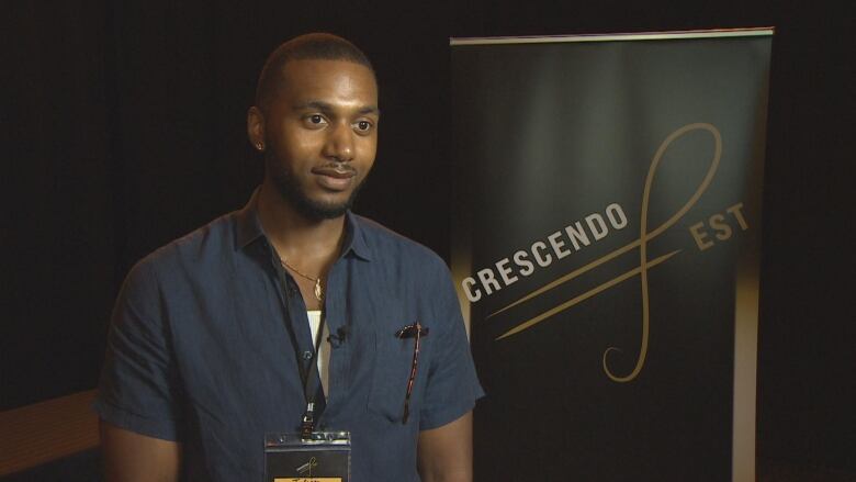 A young black man stands in front of a banner that reads Crescendo Fest.