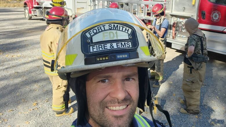 A man smiling in a fire Fort Smith EMS hat 