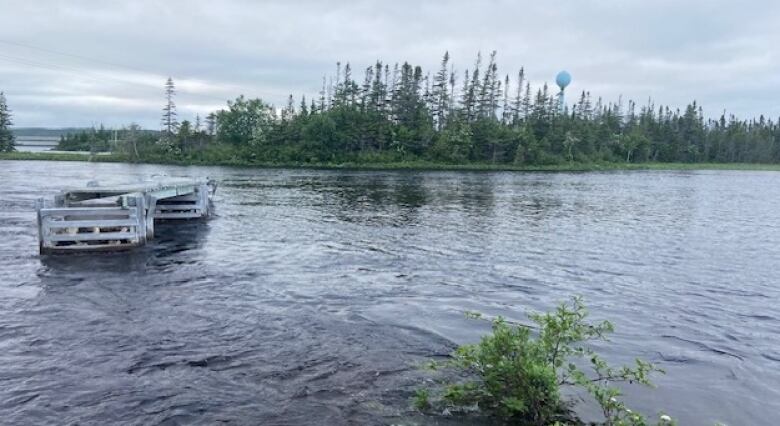 A river washes high up along the shore with a wooden structure floating in it.