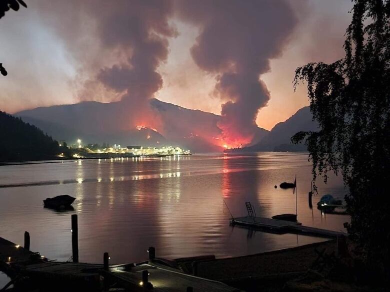 The red glow from two adjacent wildfires seen from across a lake.