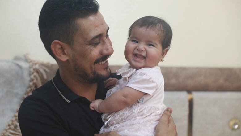 A man holds a smiling baby.