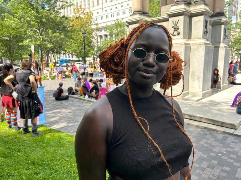 A person stands outside amid a gathering of people. 