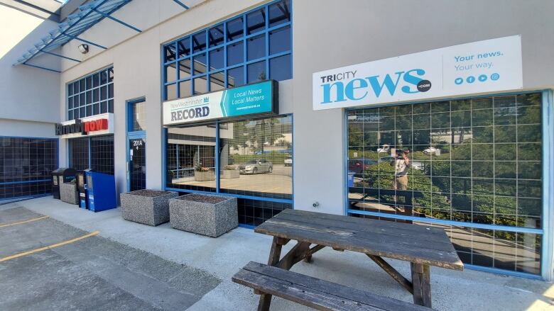 An office building with the names of each newspaper on signs outside.