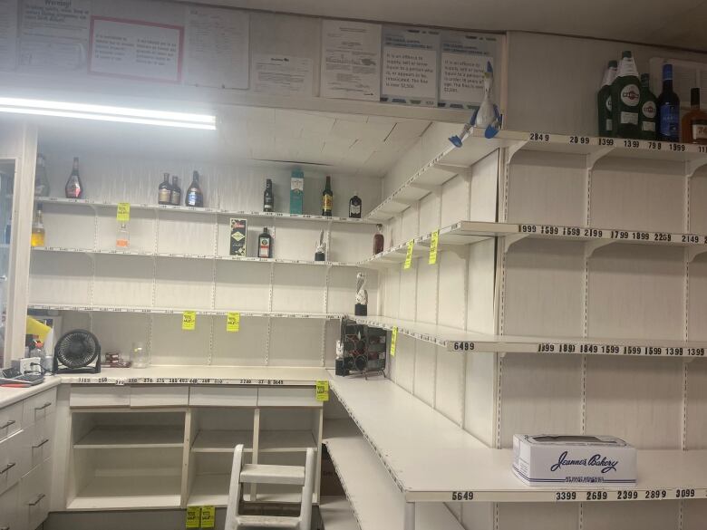 Bottles of alcohol sit on white shelves.