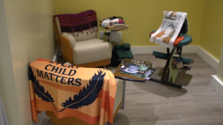 Chairs in a waiting room covered with blankets, including one that reads Every Child Matters. 