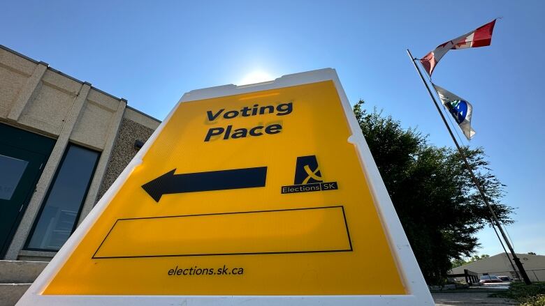 A sign in yellow that says voting place with an arrow pointing towards a door.