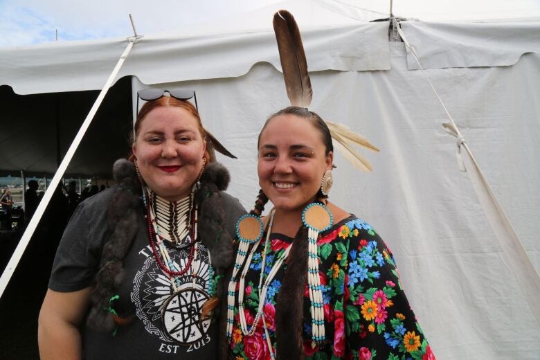 Two women stand together and smile.