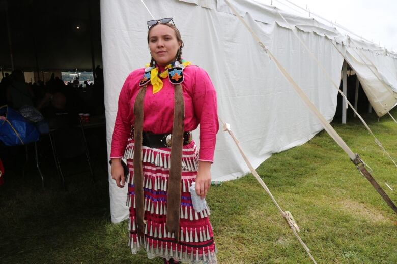 A woman stands in front of a tent.