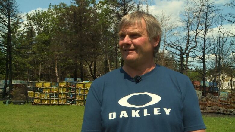 A man looks at the camera. In the background are some colourful lobster traps.