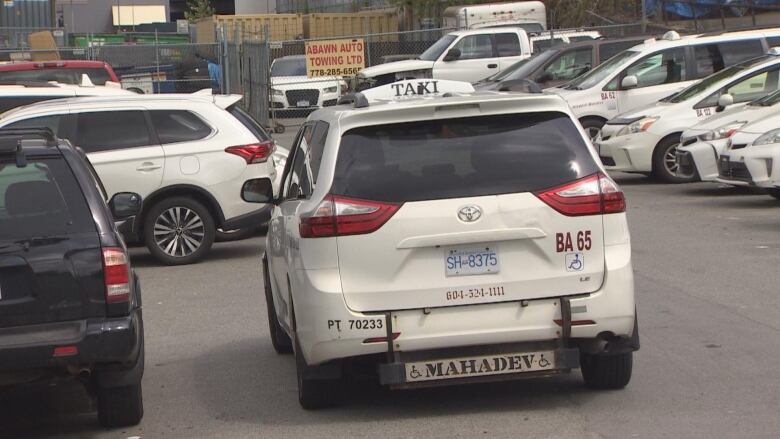 A white van taxi parked amongst other taxis