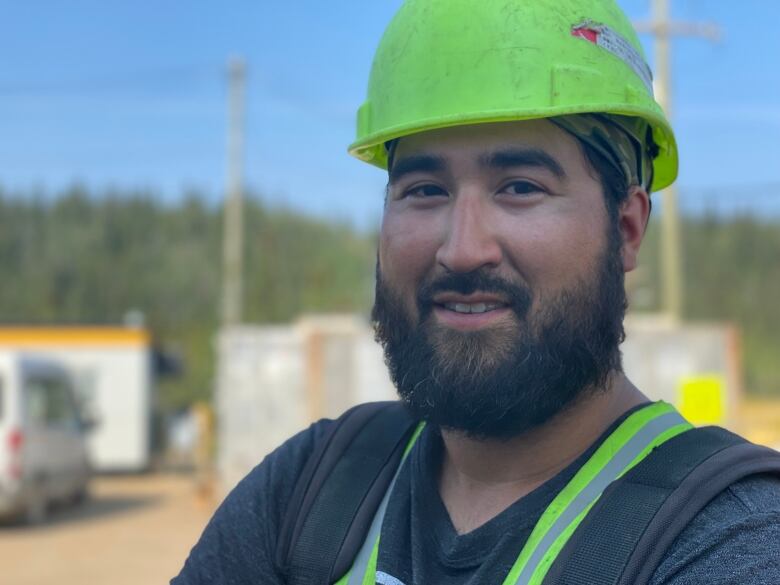 A man in a hardhat poses on a construction site.