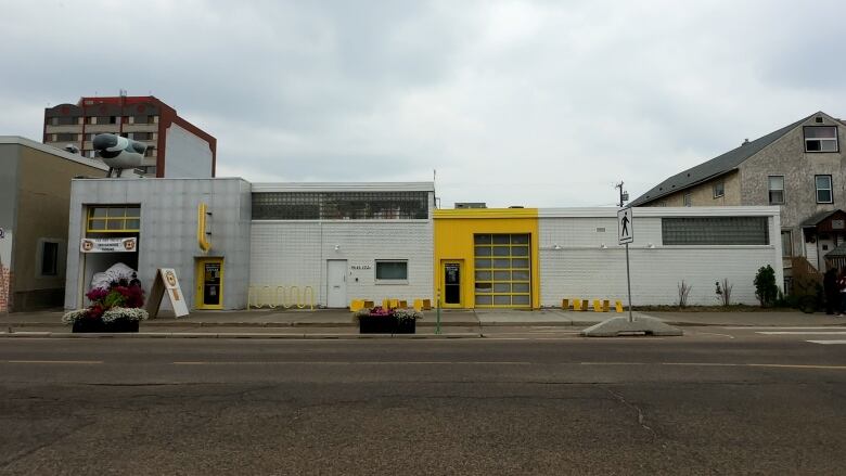 A white building with yellow accents overlooks a vacant city street. 