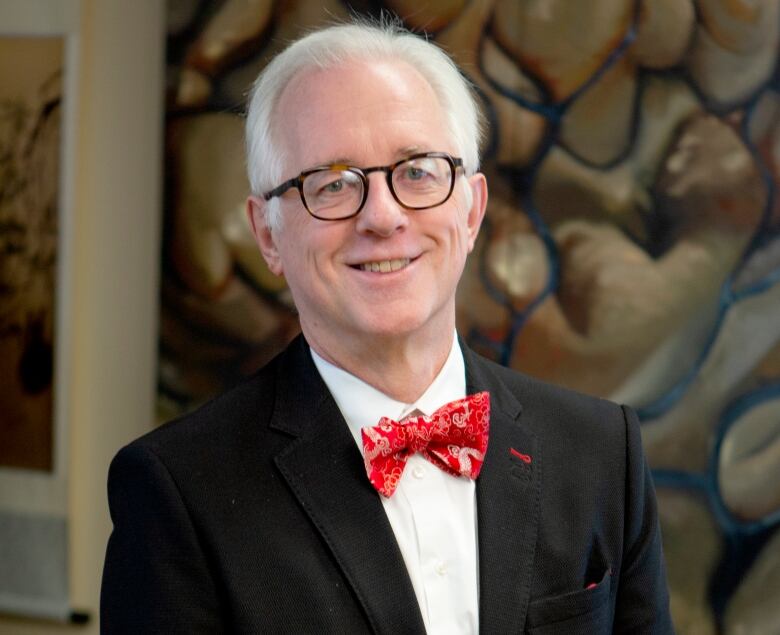 A white man with white hair smile for a portrait. 