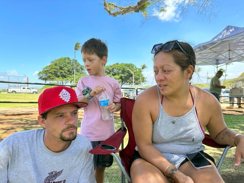 A father, mother and their son rest at an evacuation shelter after wildfires broke out on Maui.