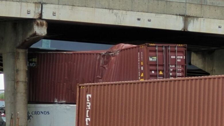 A damaged rail car under an overpass.