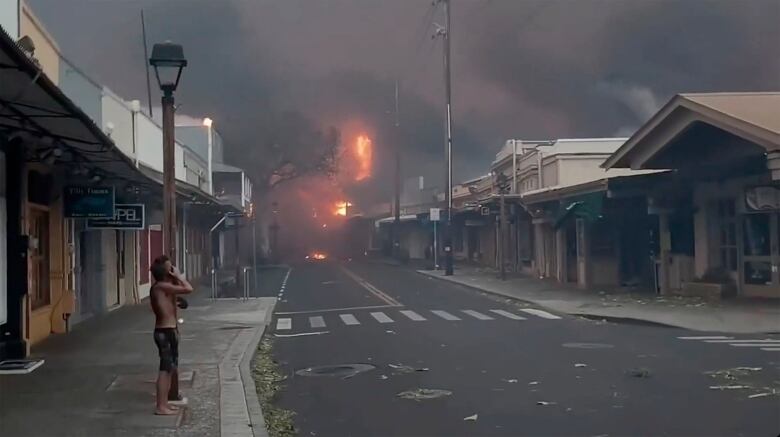 A man watches fire burn in downtown Lahaina, Maui.