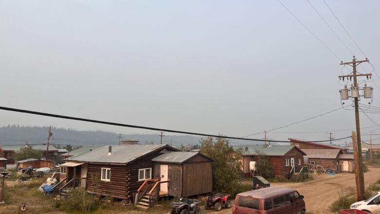 A smoky haze hangs over Old Crow, Yukon, on Wednesday. Houses, ATVs and other vehicles are seen in this photo. Residents report that the smoke has been so thick at times that they can't see across the river.