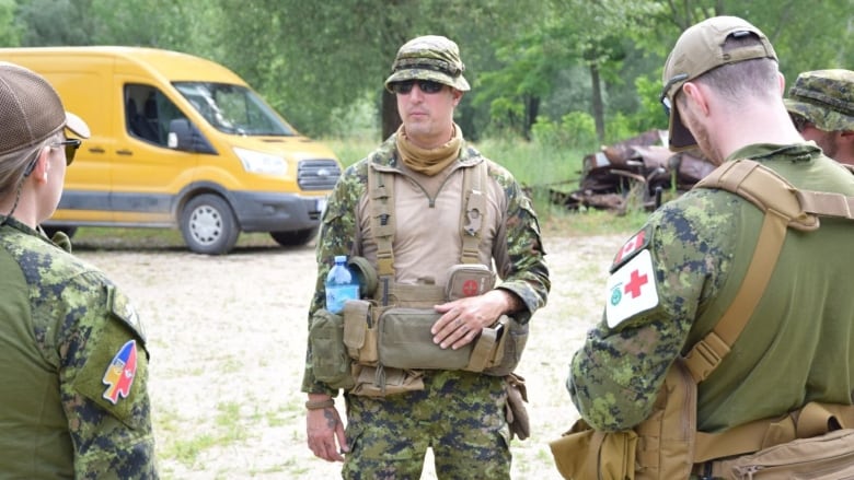 Three soldiers in uniform with one facing the camera in sunglasses. 