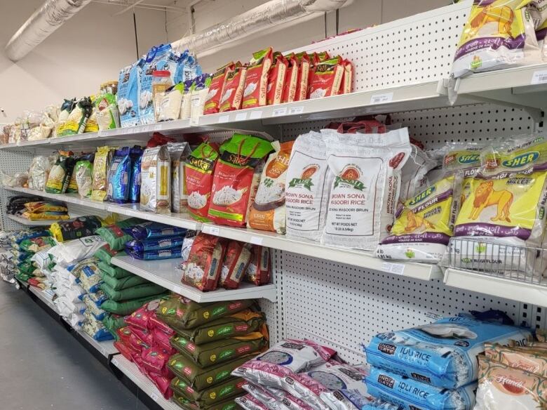 A grocery aisle with bags of rice. A few spots on the aisle are empty of product. 