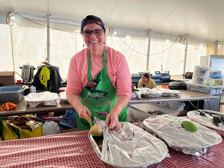 A woman unwraps foil-covered platters of food.