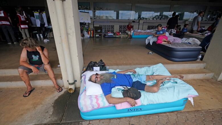 A man lays on an inflatable mattress outside a building.