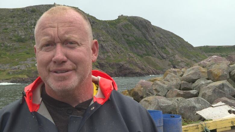 Man next to ocean and cliffs.