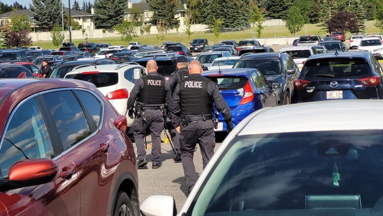 Cars at a parking lot are visible with police officers in uniform.