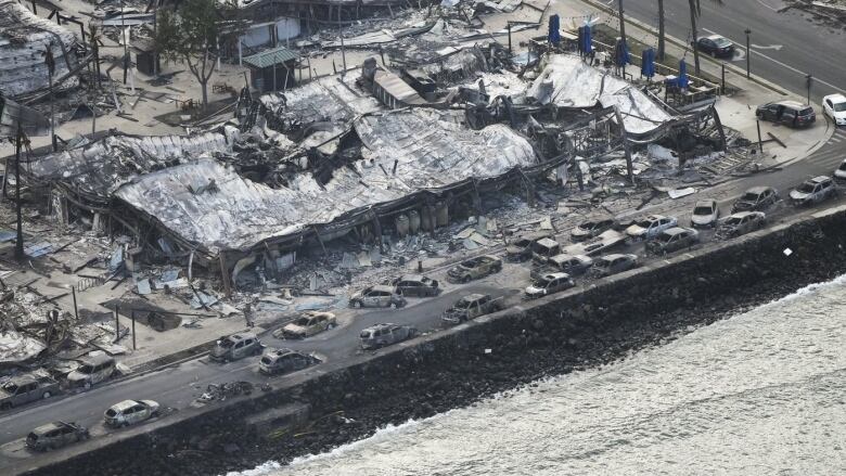 Wildfire wreckage is pictured, with burnt cars, homes and ruined infrastructure.