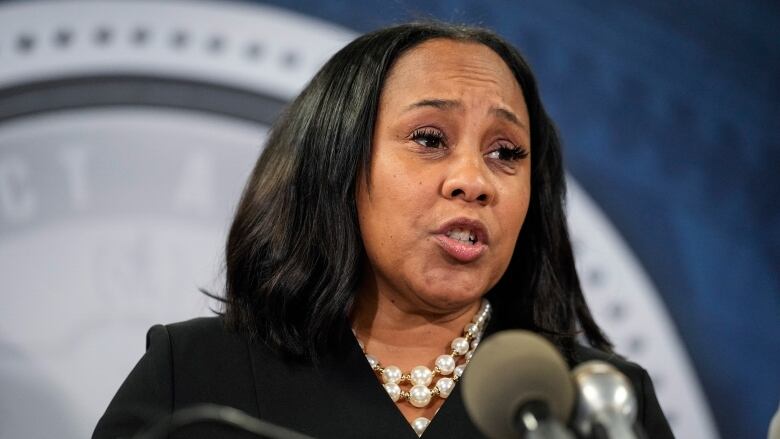 A woman is shown speaking at a podium.