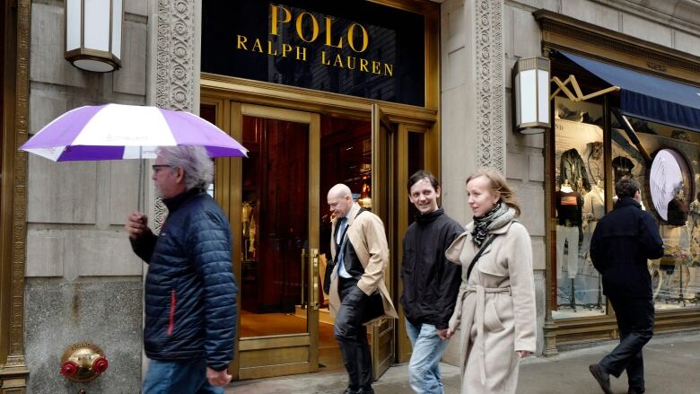 People pass the Polo Ralph Lauren store on Fifth Avenue, Tuesday, April 4, 2017, in New York. Ralph Lauren Corp. said that it is shuttering the high-profile store less than three years after opening it. The closure is part of the New York fashion company's plan to save $140 million annually. The company said it will close other stores, cut jobs and shut some corporate offices, but did not provide details. (AP Photo/Mark Lennihan)