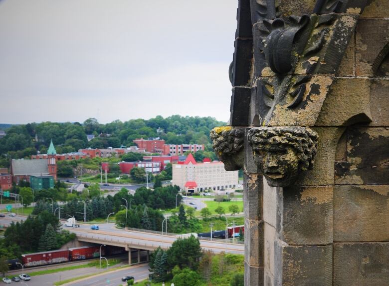 Carved stone heads on the top of a church overlook four-lane highway and the Chateau Saint John motel. 